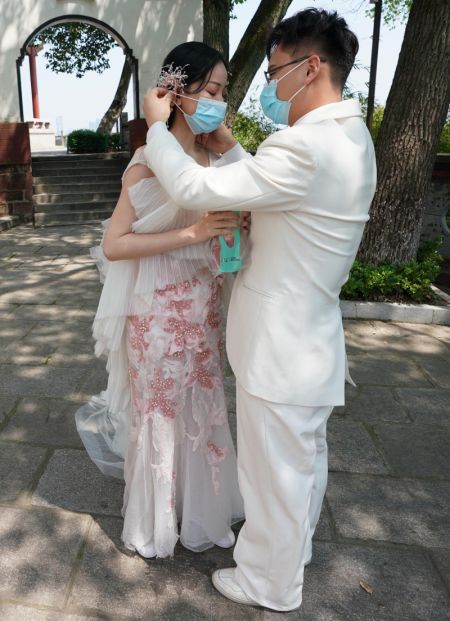 (miniature) Le nouveau marié aide son épouse à porter un masque après avoir pris des photos de mariage au pavillon Qingchuan à Wuhan