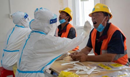 (miniature) Des professionnels de santé effectuent des prélèvements de gorge sur des ouvriers de construction dans un site de prélèvement temporaire dans l'arrondissement de Daxing