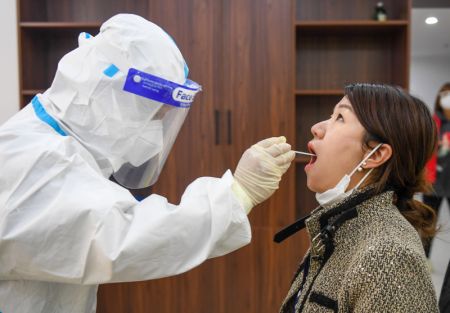 (miniature) Un professionnel de santé prélève un échantillon de gorge sur une habitante pour des tests d'acide nucléique dans un site temporaire de dépistage à Hohhot