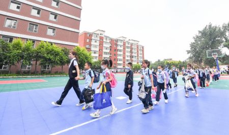 (miniature) Des élèves du primaire suivent une enseignante pour entrer dans un bâtiment d'une école à Changchun