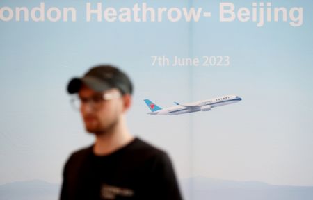 (miniature) Un membre du personnel devant une affiche géante pour la cérémonie d'inauguration de la liaison aérienne directe entre Londres et Beijing de la compagnie aérienne chinoise China Southern Airlines qui se tient à Londres