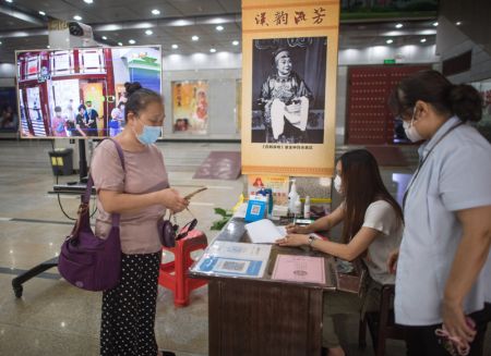 (miniature) Une femme subit un contrôle de température corporelle et s'enregistre avant d'entrer dans le théâtre Renmin