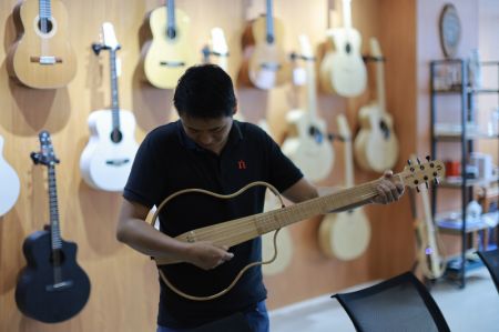 (miniature) Un travailleur contrôle une guitare dans le Parc industriel de guitares de Zheng'an