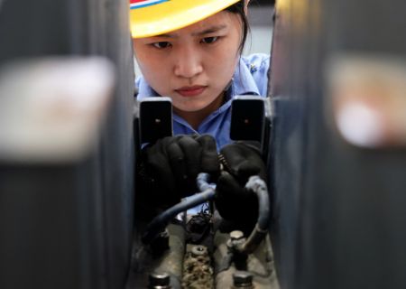 (miniature) Une ouvrière de maintenance réalise des travaux d'assemblage sur le couvre-culasse d'un train dans l'atelier de maintenance nord du dépôt de locomotives de Zhengzhou