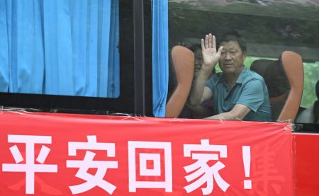(miniature) Des villageois font des signes de la main à bord d'un bus en rentrant chez eux depuis un site de relogement de l'arrondissement de Xiqing