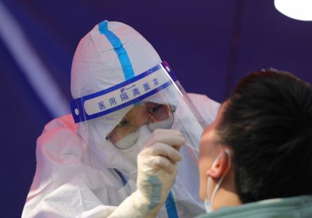 (miniature) Un membre du personnel m&eacute;dical pr&eacute;l&egrave;ve un &eacute;chantillon de gorge sur un habitant dans un site de d&eacute;pistage de la COVID-19 &agrave; Xining
