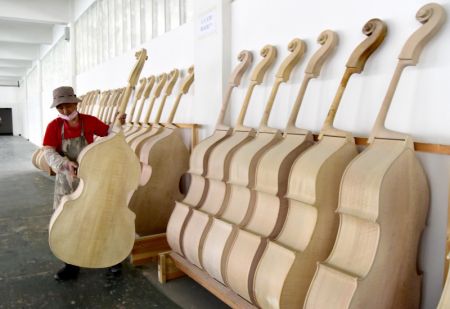 (miniature) Un ouvrier travaille dans un atelier dans un parc industriel de production d'instruments de musique à Queshan