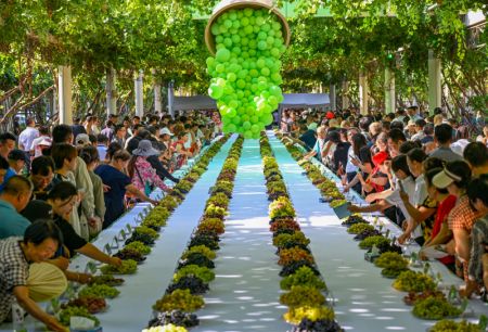 (miniature) Des personnes dégustent des raisins lors d'une foire aux raisins à Turpan