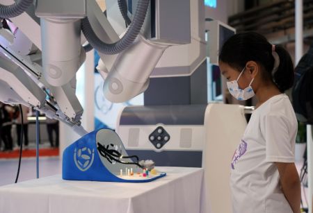 (miniature) Une jeune fille devant un robot chirurgical lors de la Conférence mondiale sur la robotique 2022