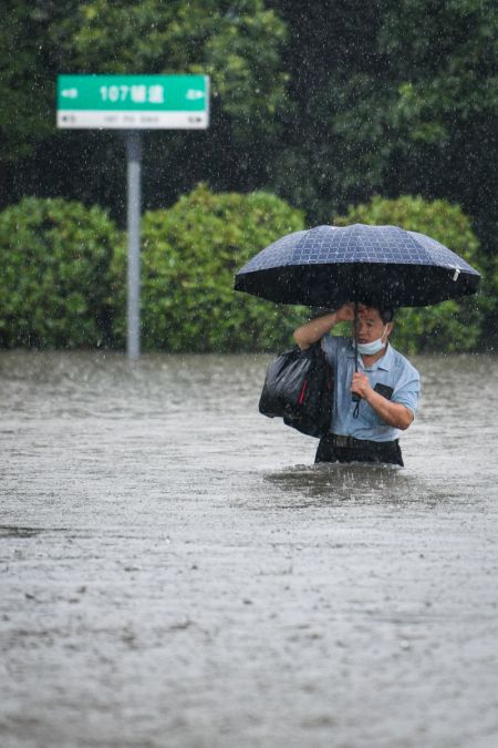 (miniature) Un homme traverse une rue inondée de Zhengzhou