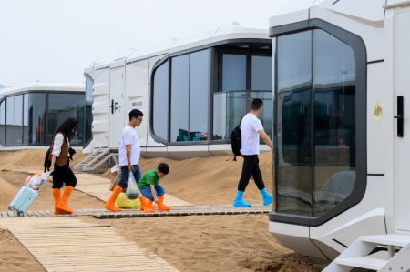 (miniature) Des touristes entrent dans un campement de capsules hôtelières dans le site touristique du désert de Yinkentala