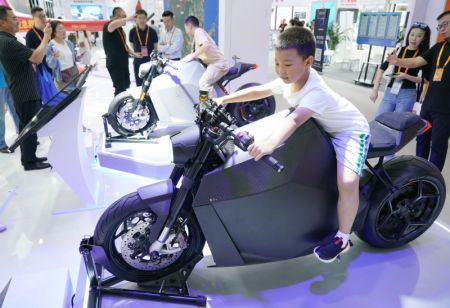 (miniature) Un garçon essaie une moto électrique durant la Foire internationale du commerce des services de Chine (CIFTIS) 2023 au parc Shougang