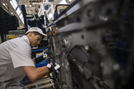 (miniature) Un ouvrier installe des câbles sur un véhicule sur une chaîne de montage de la société Dongfeng Motor Corporation