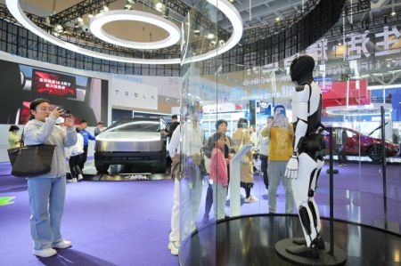 (miniature) Des gens regardent un robot de Tesla lors d'une exposition organisée dans le cadre des célébrations en Chine de la Journée mondiale des villes 2024