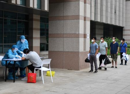 (miniature) Des gens qui ont terminé le confinement attendent d'obtenir des documents avant de quitter un site de confinement désigné à Beijing