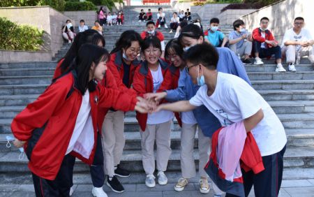 (miniature) Des candidats s'encouragent mutuellement à l'extérieur d'un site d'examen dans un lycée du district autonome Miao de Songtao