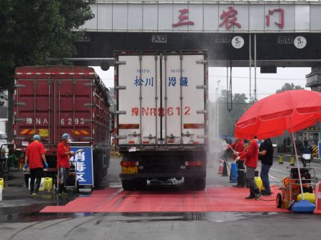 (miniature) Des membres du personnel désinfectent un véhicule sortant du marché Xinfadi