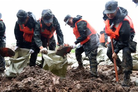 (miniature) Des policiers arm&eacute;s remplissent des sacs de sable sur la digue de la rivi&egrave;re Shiba