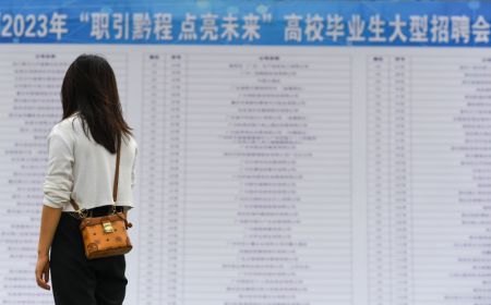 (miniature) Une diplômée d'université lit des informations sur le recrutement lors d'un salon de l'emploi dans la préfecture autonome Miao et Dong de Qiandongnan