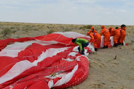 (miniature) Des membres du personnel récupèrent les parachutes de la capsule de retour de la version d'essai du vaisseau spatial habité chinois de nouvelle génération sur le site d'atterrissage de Dongfeng