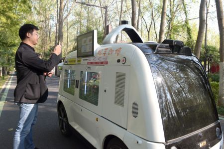 (miniature) Un touriste scanne le code QR d'un véhicule de vente sans conducteur pour faire des achats dans le parc forestier national de Binhu