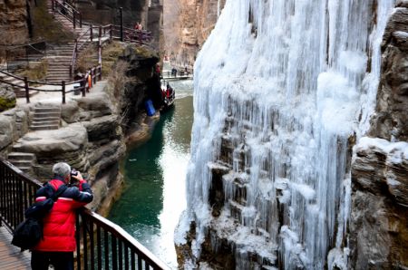 (miniature) Un visiteur prend des photos de chutes d'eau gelée de la montagne de Yuntai