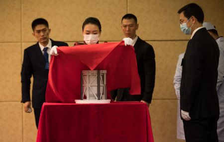 (miniature) Une employée recouvre d'un voile le conteneur des échantillons lunaires lors de la cérémonie de transfert des échantillons lunaires de Chang'e-5 à l'Administration nationale de l'espace de Chine