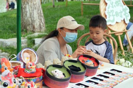 (miniature) Un enfant met en couleur un Tuye (figurine traditionnelle chinoise et symbole de bonne augure) dans le parc Longtan dans l'arrondissement de Dongcheng à Beijing