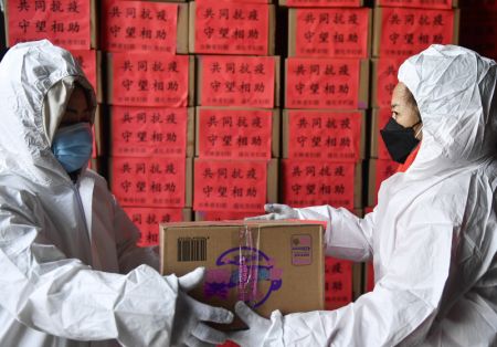 (miniature) Deux employées déchargent des dons de produits de première nécessité qui viennent d'arriver dans une résidence de travailleurs médicaux à Tonghua