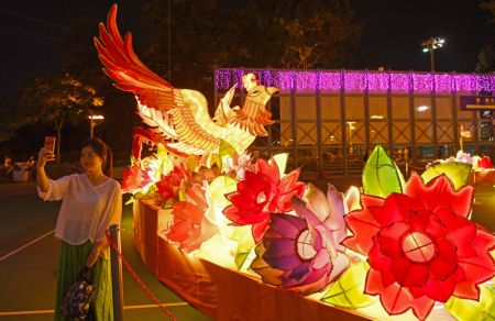 (miniature) Une femme prend des selfies lors d'une foire des lanternes organisée à l'approche de la Fête de la mi-automne et de la Fête nationale