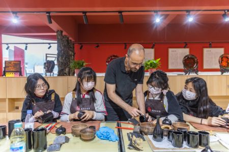 (miniature) L'artiste français Vincent Cazeneuve enseigne l'art de la laque à des élèves dans un centre de formation professionnelle du district de Chengkou