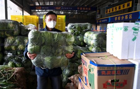 (miniature) Un membre du personnel transporte des légumes dans un centre logistique à Xi'an