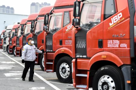 (miniature) Un ouvrier contrôle un véhicule en attente de livraison sur un parking de FAW Jiefang