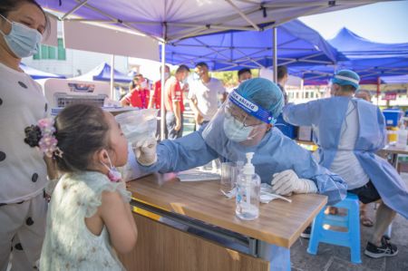 (miniature) Un professionnel de santé prélève un échantillon sur une enfant pour un test d'acide nucléique dans le Nouvel Arrondissement de Liangjiang