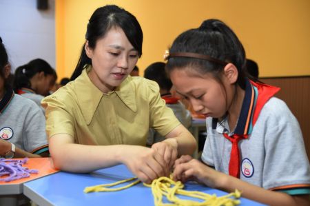 (miniature) Zhao Xun (à gauche) enseigne des techniques de tricotage à une élève au club de tricotage de l'Ecole primaire Luogang