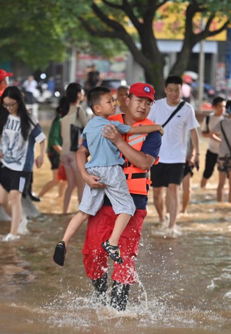 (miniature) Un secouriste aide un enfant à évacuer une zone inondée à Guilin