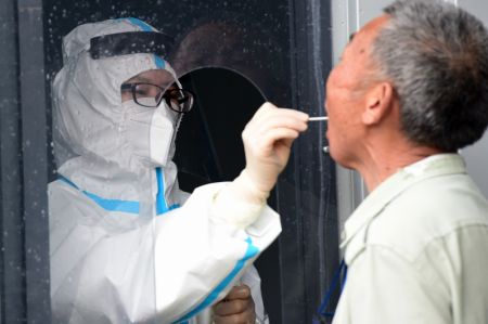 (miniature) Un membre du personnel médical prélève un échantillon de gorge sur un habitant pour des tests d'acide nucléique dans un hôpital dans le district de Feixi
