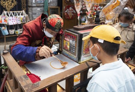 (miniature) Un enfant assiste à la fabrication de décorations en sucre dans un site pittoresque à Harbin