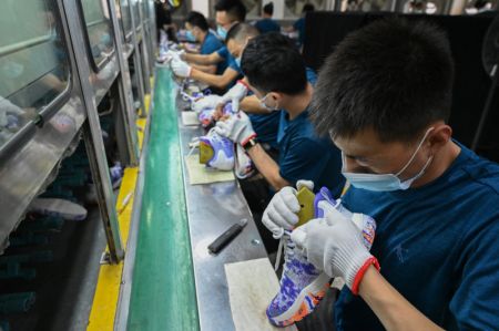 (miniature) Des employés travaillent sur une ligne de production d'une entreprise de chaussures de sport
