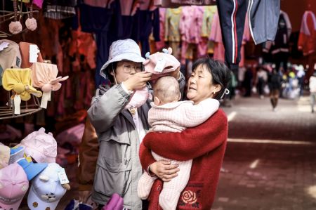 (miniature) Une cliente choisit un chapeau pour son bébé dans un bazar hebdomadaire du bourg de Tokkuzak