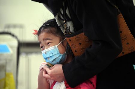 (miniature) Une enfant reçoit une dose de vaccin contre la COVID-19 dans un site de vaccination dans l'arrondissement de Haidian à Beijing