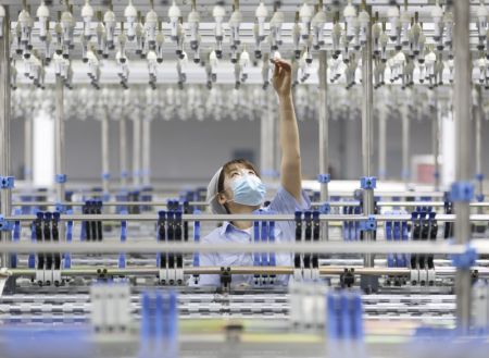 (miniature) Une ouvrière effectue des réglages sur une machine dans une usine d'un parc industriel de l'arrondissement de Jimo