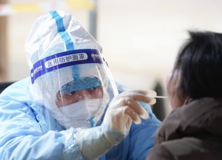 (miniature) Un travailleur médical prélève un échantillon sur un habitant dans un site de dépistage du COVID-19 de l'arrondissement de Daxing