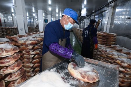(miniature) Un employé prépare des jambons dans une usine alimentaire de l'arrondissement de Jindong