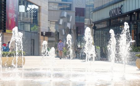 (miniature) Une habitante marche près d'une fontaine dans un contexte de température élevée