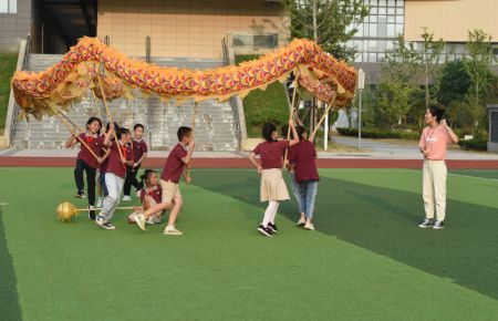 (miniature) Wang Ling (1re à droite) donne des instructions à ses élèves au club de danse du dragon et du lion de l'Ecole primaire Heping