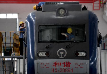 (miniature) Des ouvriers de maintenance réalisent des travaux sur un train dans l'atelier de maintenance nord du dépôt de locomotives de Zhengzhou