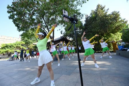 (miniature) Des habitants pratiquent la danse en groupe près des remparts anciens de Xi'an