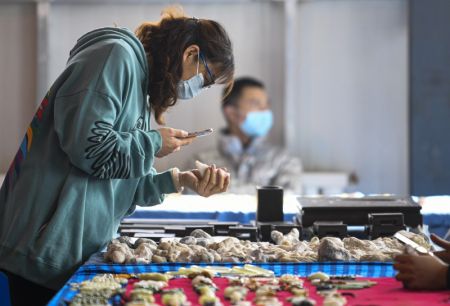 (miniature) Une femme sélectionne des pierres rares dans un bazar de Hami