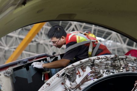 (miniature) Un technicien de HNA Technic en plein exercice d'entretient d'un avion entrant à la base de maintenance aéronautique du Port de libre-échange de Hainan à Haikou